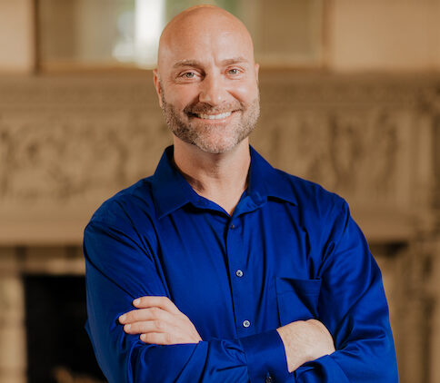 Bald man posing with arms crossed.